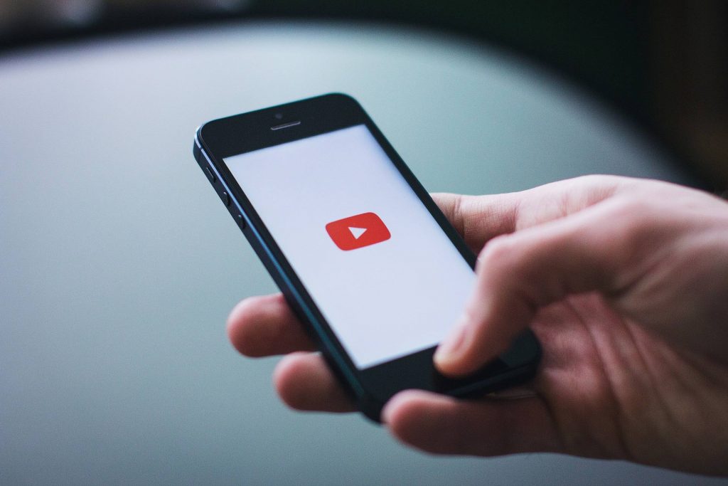 osoba drzi telefon u ruci sa logoom youtube